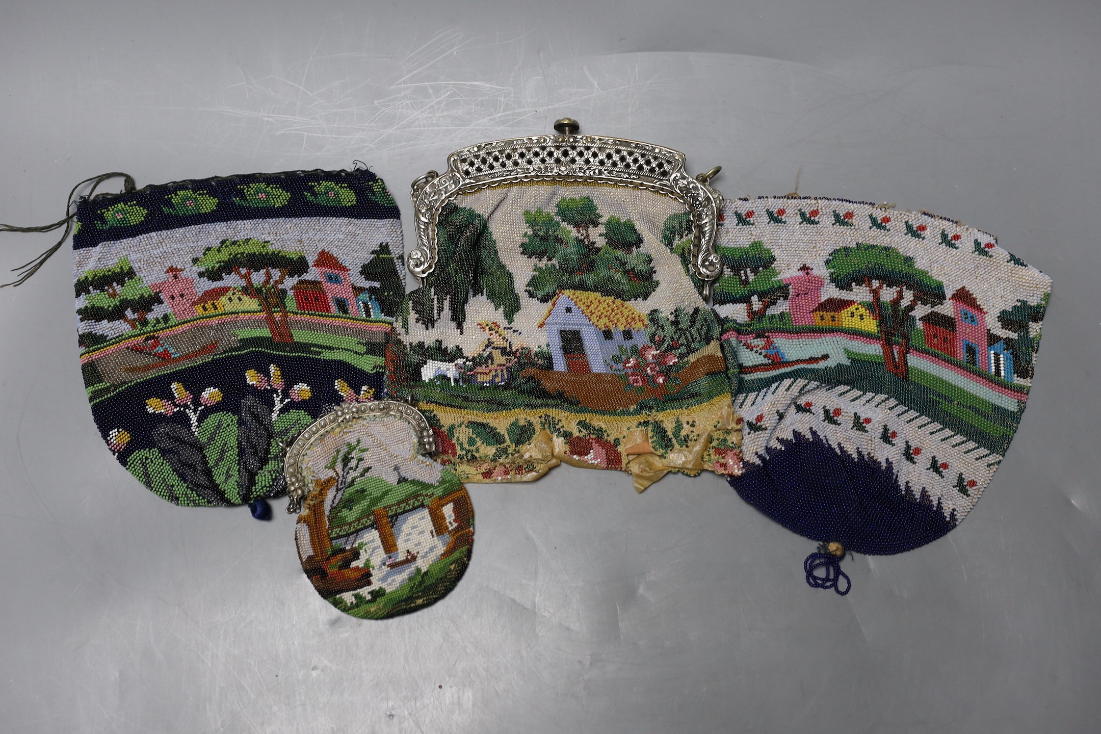 Three beaded bags/reticules, circa 1835-45 and a similar purse, all worked in multi coloured beads depicting tree lined landscapes with houses rivers and figures, possibly American, (4), framed bag 17 cms high